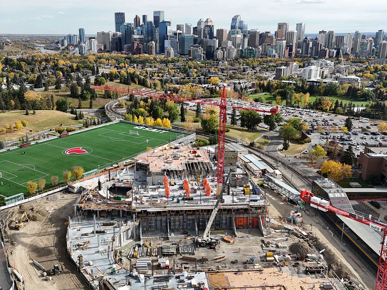 aerial view of the taylor family campus centre construction site, two large red cranes are surrounded on the ground with heavy vehicles and construction supplies