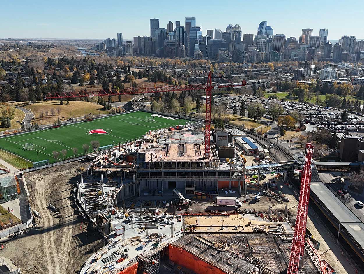aerial view of the taylor family campus centre construction site, two large red cranes are surrounded on the ground with heavy vehicles and construction supplies