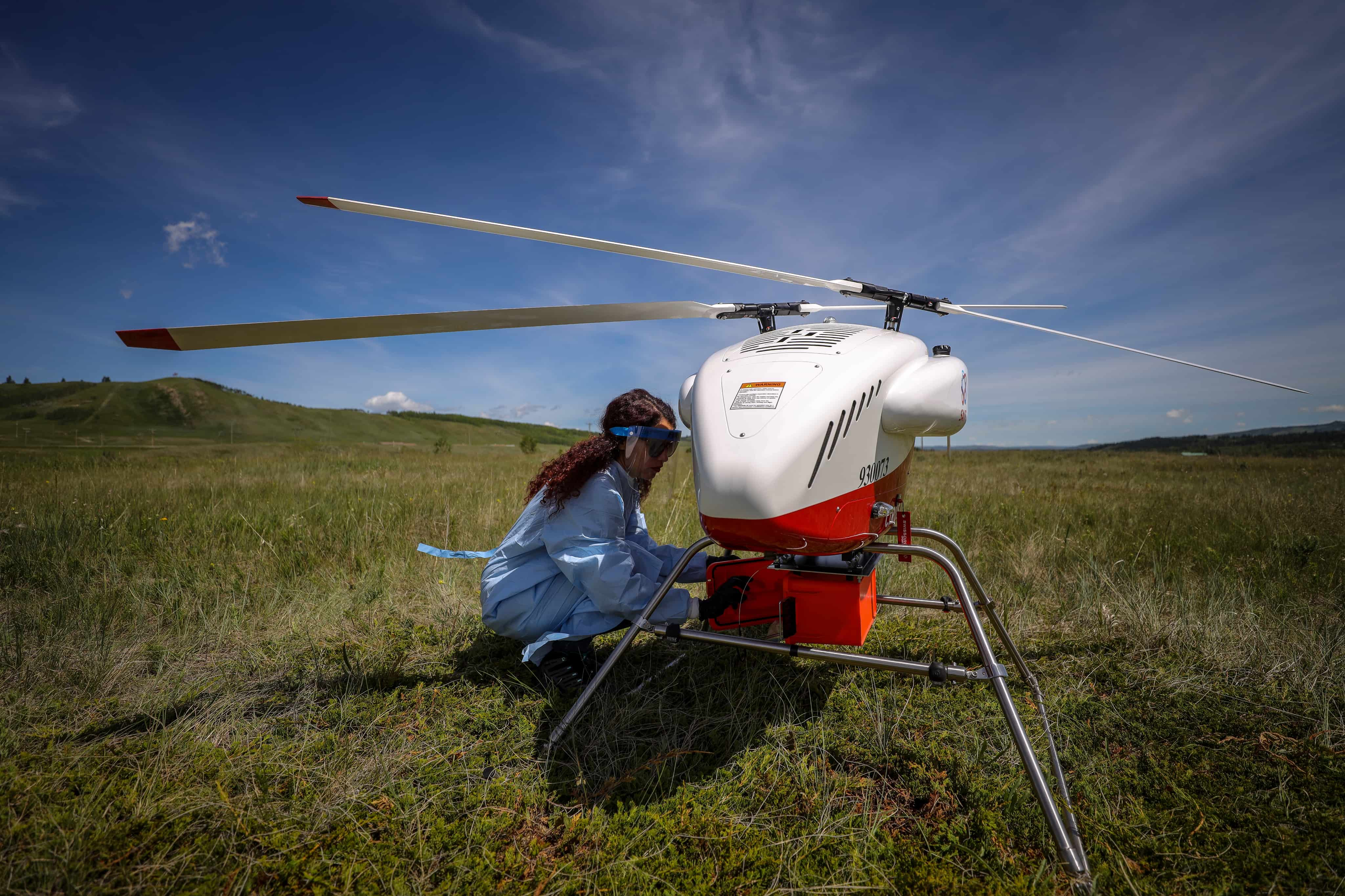 A drone in a field being inspected by a student