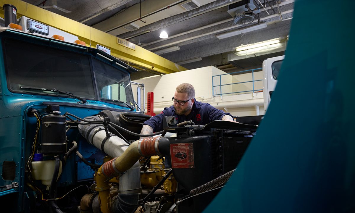 worker repairing a truck engine in an industrial workshop