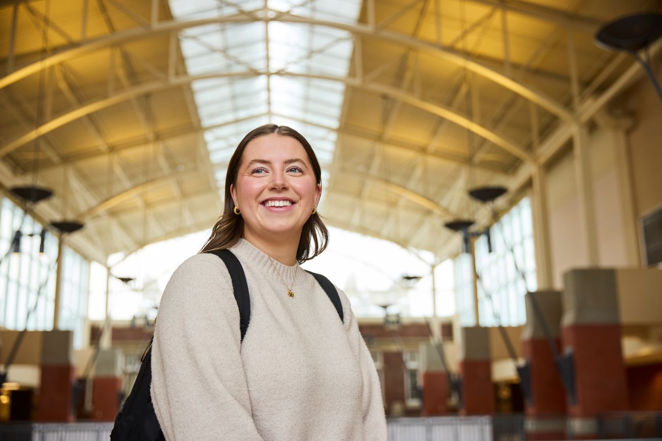 A girl wearing a cream color shirt smiling away from the camera