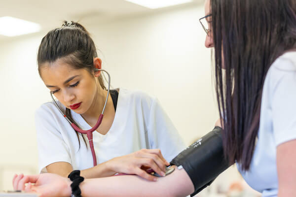 A nurse listens to a patients blood pressure.