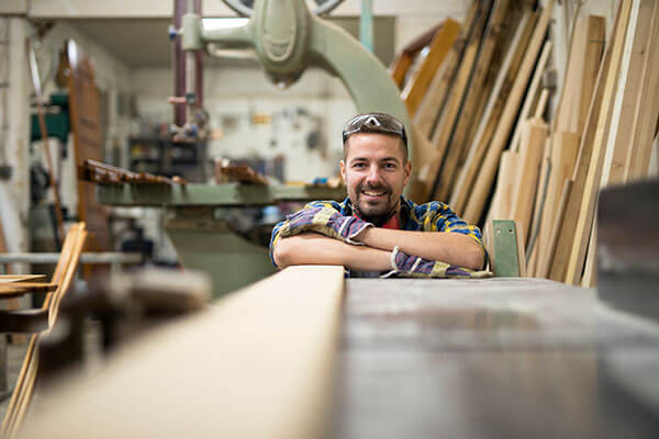 A student crosses his arms over a plank of wood in a woodworking lab at SAIT.