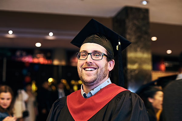 A graduate from the SAIT School of Hospitality and Tourism wearing his cap and gown.