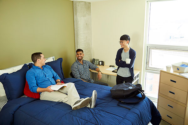 Three students hang out in a room in the Begin Tower.