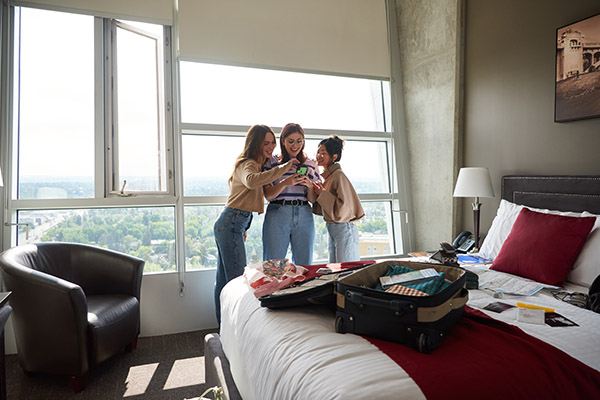 Three students gather inside a room in Residence on SAIT campus.