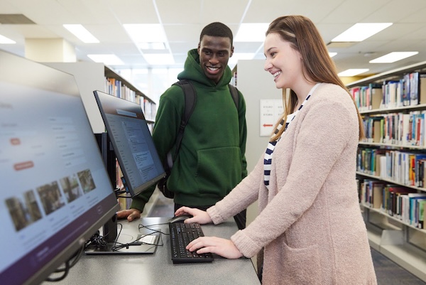 Two people standing around a computer