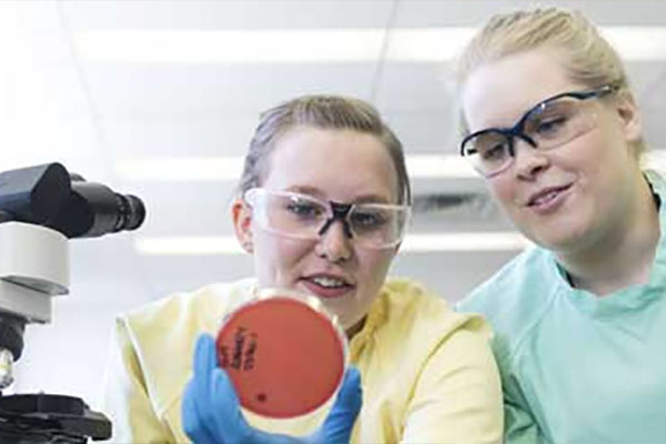 Two Medical Laboratory Technology students look at a sample in a dish.