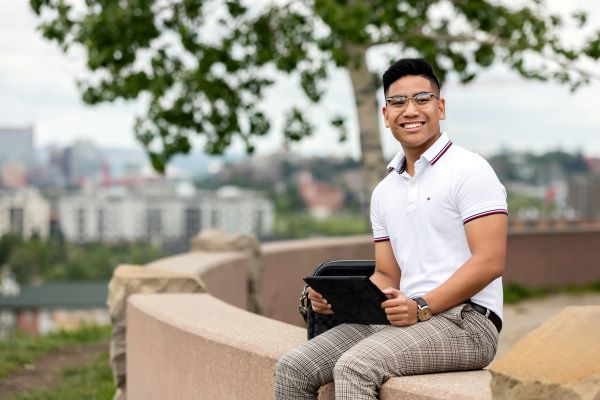 A man holding a tablet while sitting outdoors 