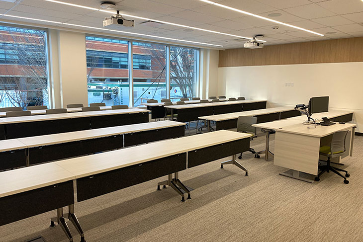 rows of desks and chairs in a classroom with a large windows at the back