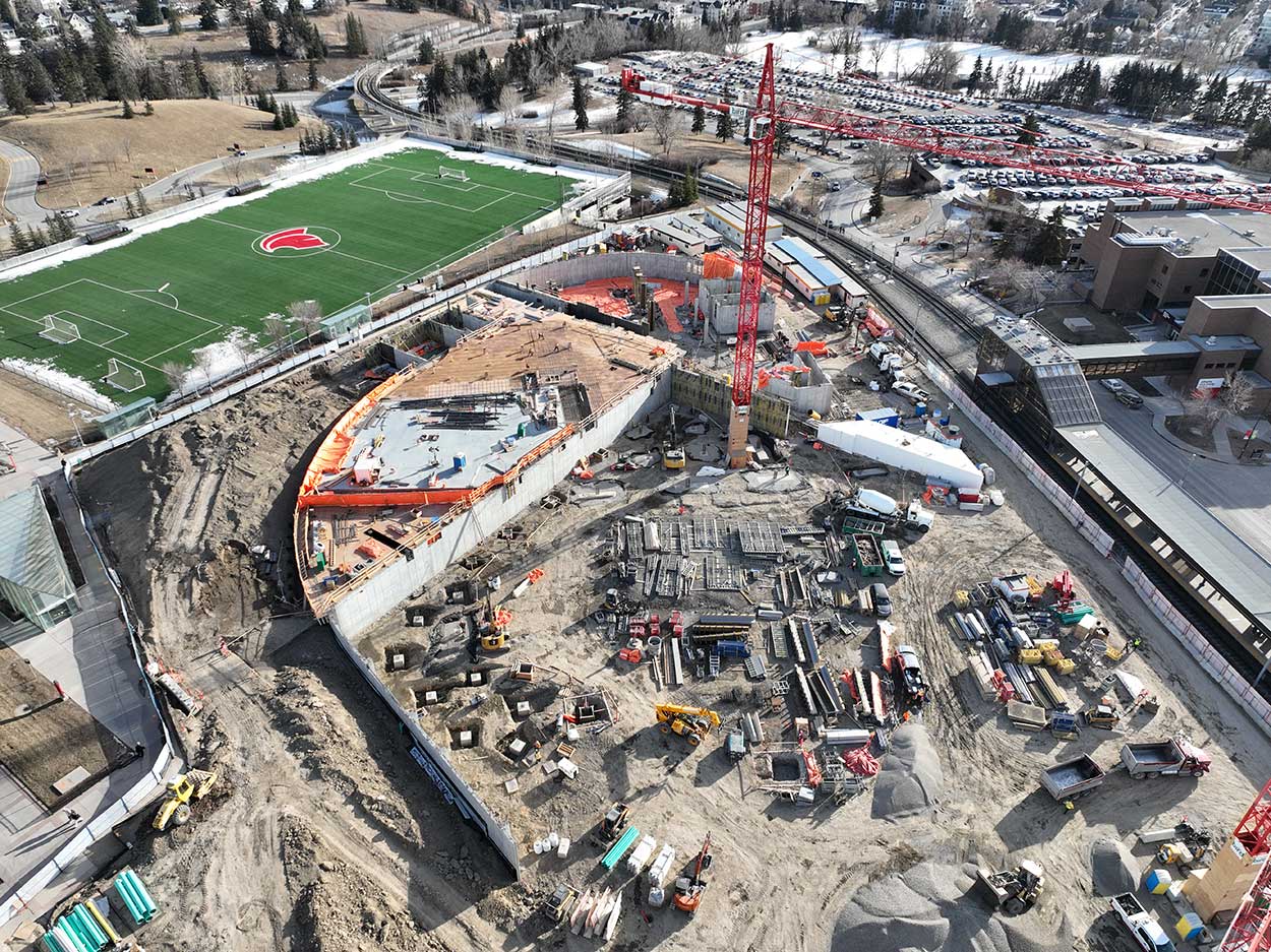 aerial view of the taylor family campus centre construction site, a large red crane is surrounded by construction materials and partially completed concrete foundations