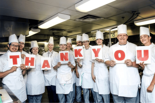 Youth culinary students holding signs to say thank you