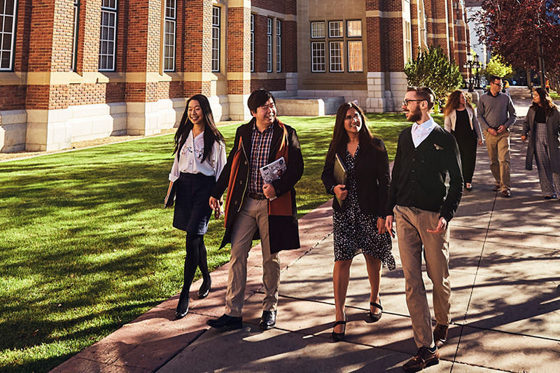 A group of SAIT students look at a computer while sitting outside Heritage Hall.