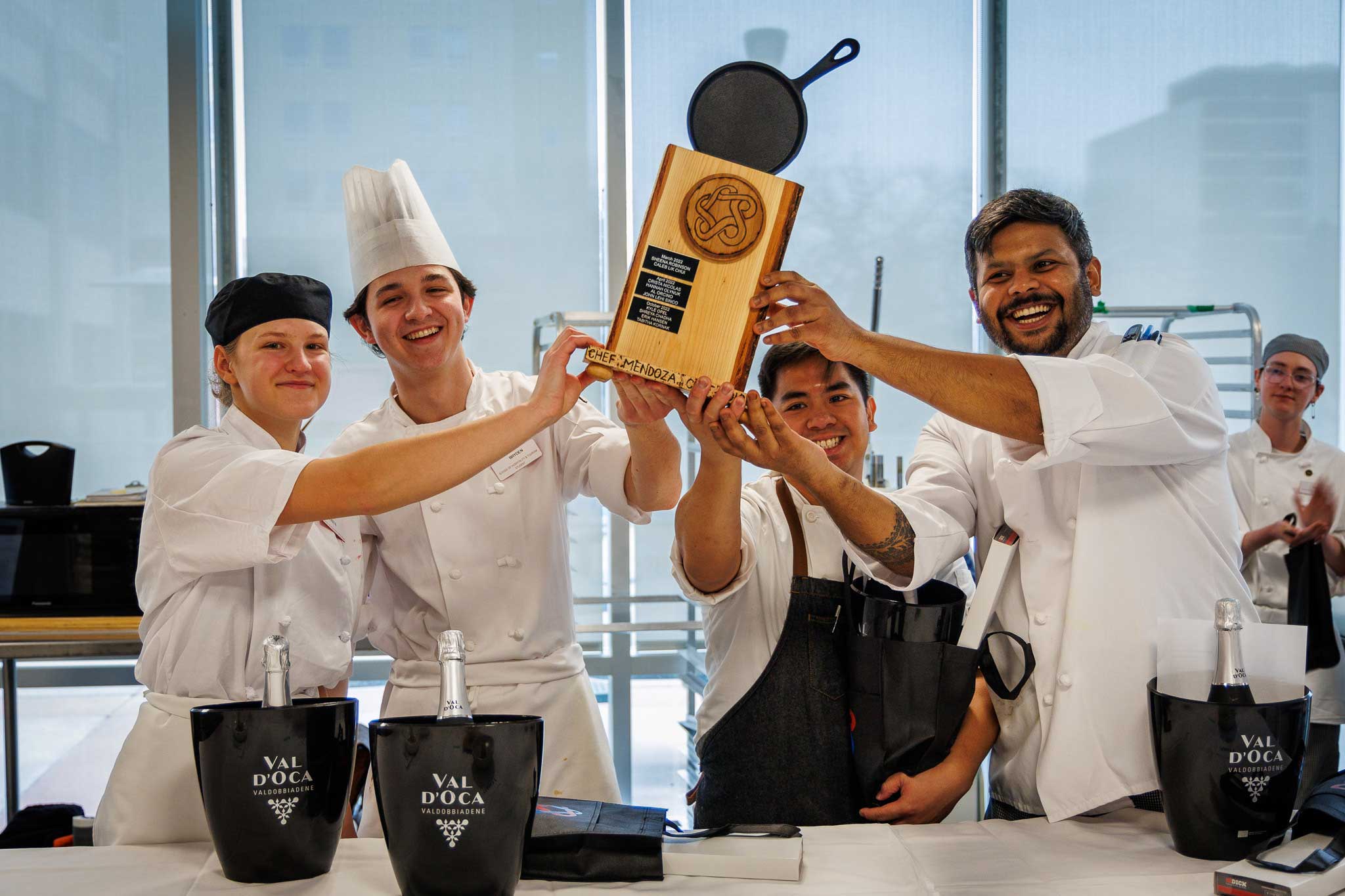 A culinary arts instructor shapes pizza dough in the 4Nines Kitchens while a student and instructor watch