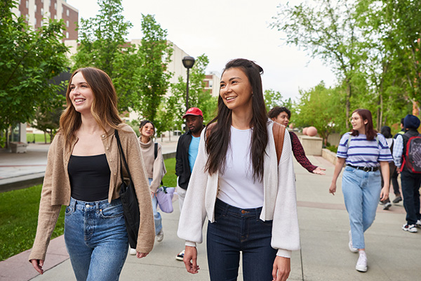 A diverse group of students walking together on a campus pathway, showcasing friendship and community.
