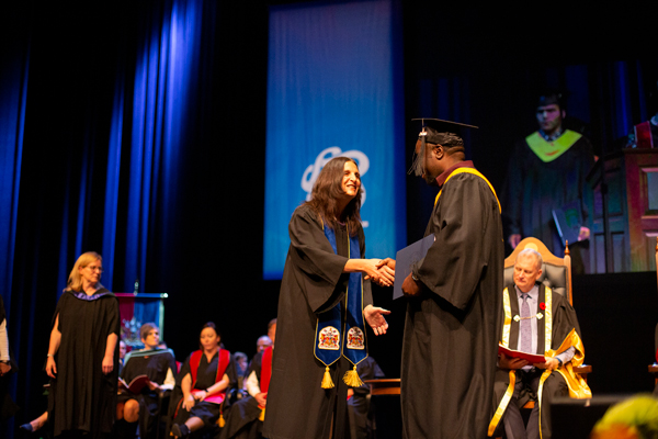 A SAIT graduate shakes hands with their Academic Chair during convocation.