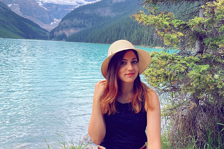 Woman wearing hat sitting in front of lake
