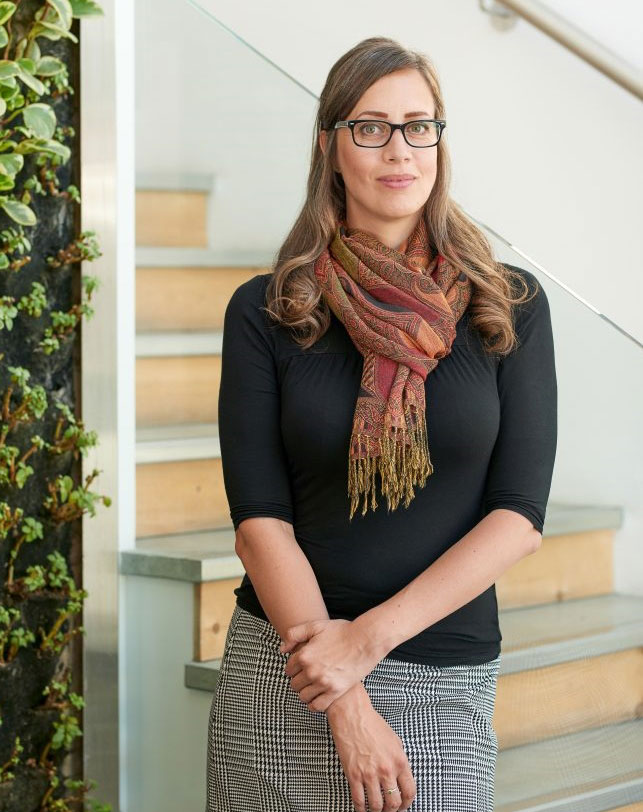 Tracy Chala white female posing for camera wearing glasses, black top, white and black checkered skirt and has long haird