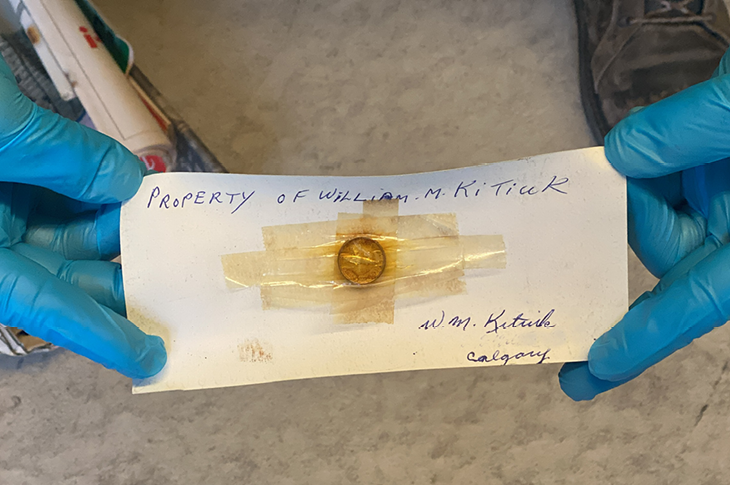 A major clue within the package, a note — Property of William M. Kitiuk — and a 1967 centennial dime.