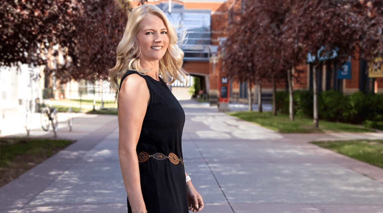 Linda Olsen turning over shoulder to look at camera wearing a black dress