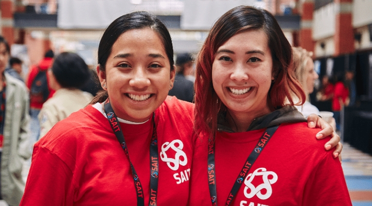 Two female volunteers wearing red tshirts smiling