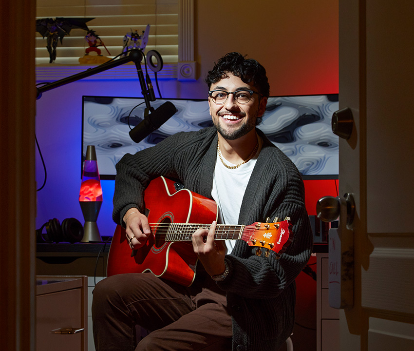 Young man siting with red guitar in personal home studio