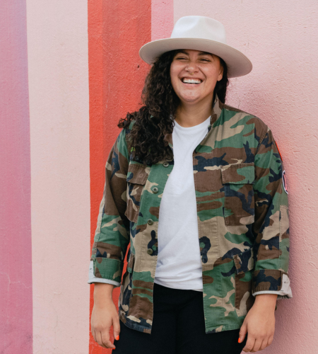 young woman wearing camo and white hat laughing