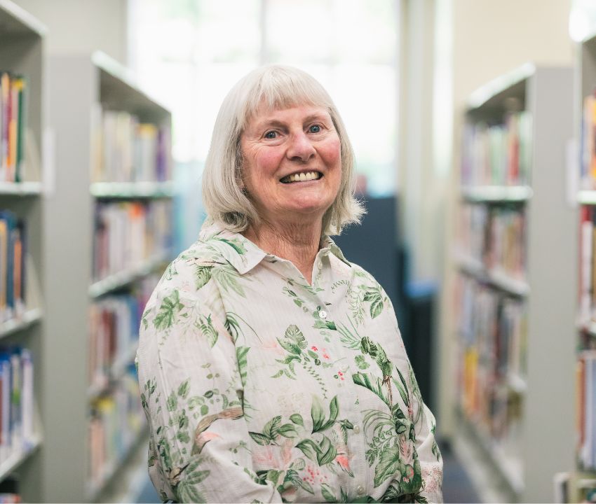 Mature woman with white hair standing in library