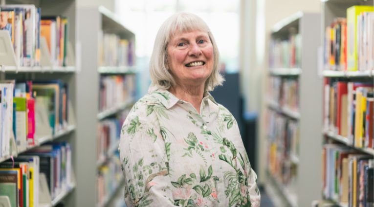 Mature woman with white hair standing in library