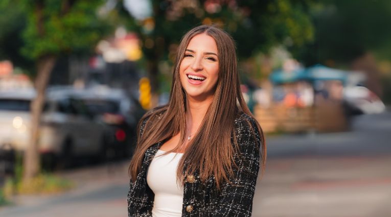 young woman with long brown hair laughing outside