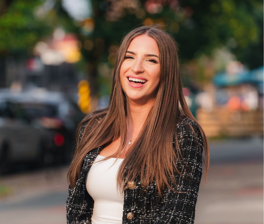 young woman with long brown hair laughing outside