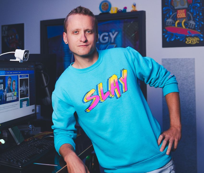 photo of young man in blue sweater with the word slay on the front