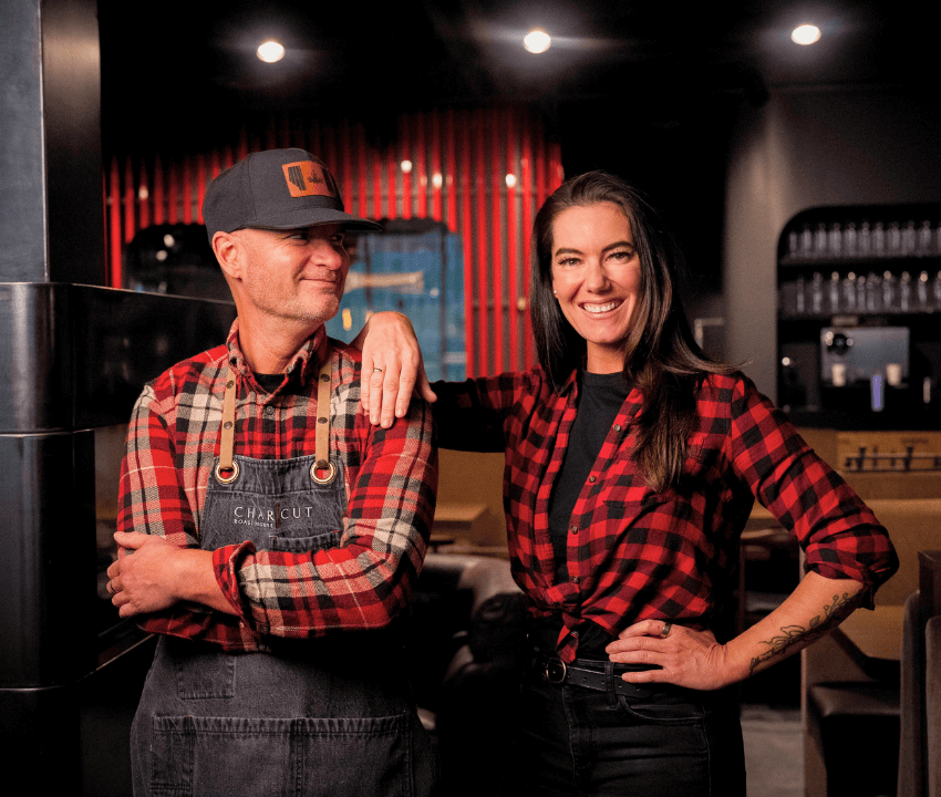 male and female chefs wearing plaid shirts and aprons smiling