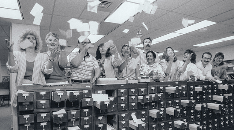 Archival photo of library staff throwing cards in the air