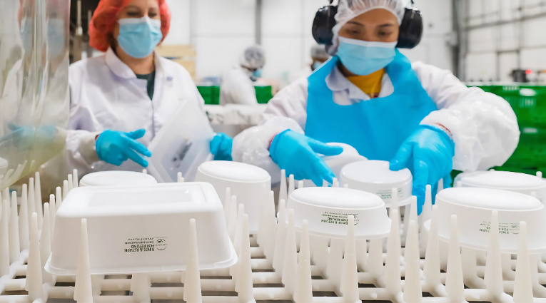 two workers stacking reusable containers on a rack