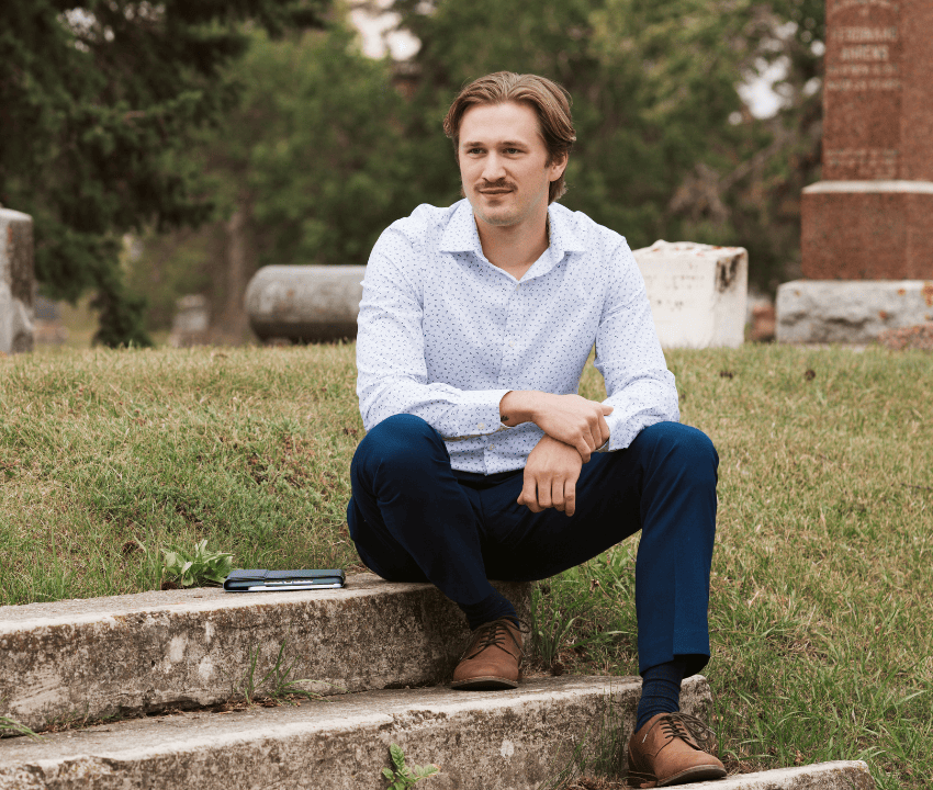 young white man sitting on steps in a graveyard