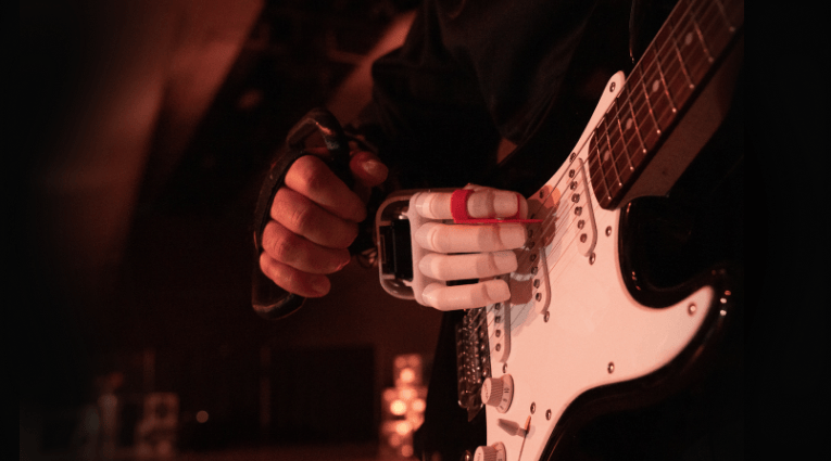 close up of a person playing a guitar with a bionic hand