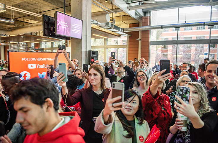 Students, staff, sponsors and other guests watch SAIT's Giving Day augmented reality mural come to life on their phones through the Augle App.