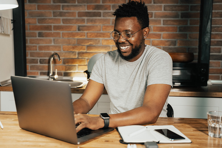 man smiling while typing on laptop