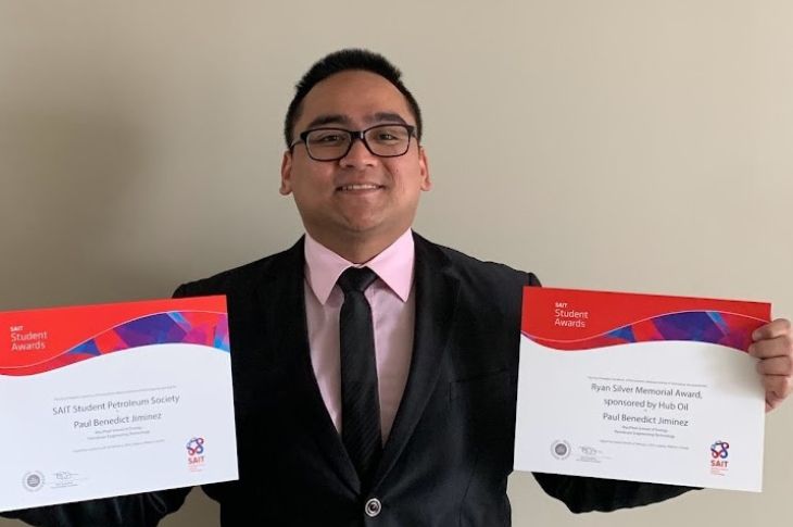 Paul Jimenez smiles as he holds his two student awards.