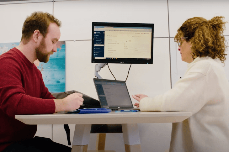 A man and a women are sitting at a table with a laptop