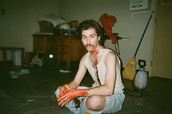 A behind-the-scenes photo: a film student sits covered in fake blood in a SAIT classroom.