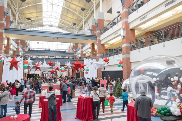 The Irene Lewis Atrium interior is decorated with many tables for guests that include large plastic domes that look like snowglobes. There are paper stars hanging from the ceiling in white, red and green.