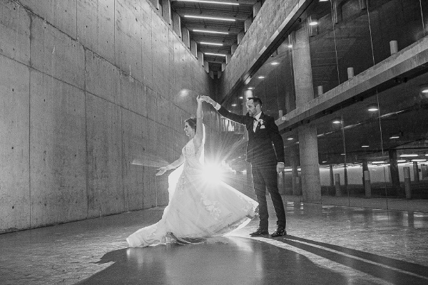 A black and white photo of a bride and groom dancing in the SAIT parking lot.