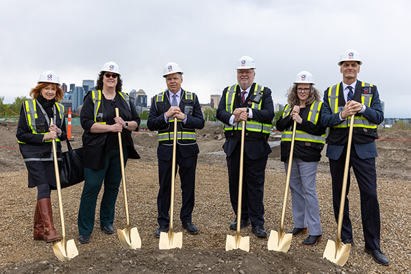 SAIT Executives pose in hard hats holding shovels at a construction site