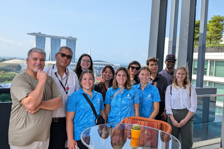 Students gather on a patio of a boutique hotel in Singapore. You can see the Marina Bay Sands in the background.