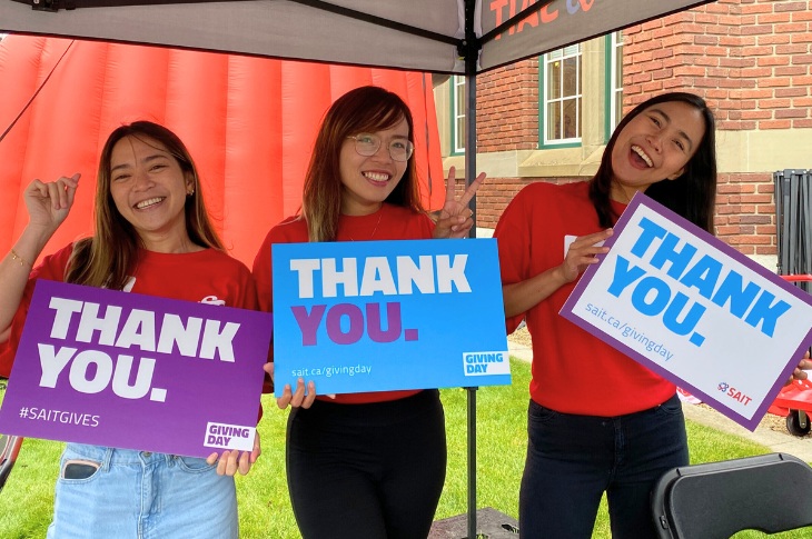 three people holding thank you signs