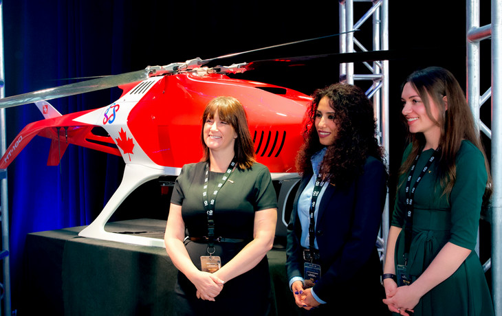 The people stand together for a photo in front of a red RPAS