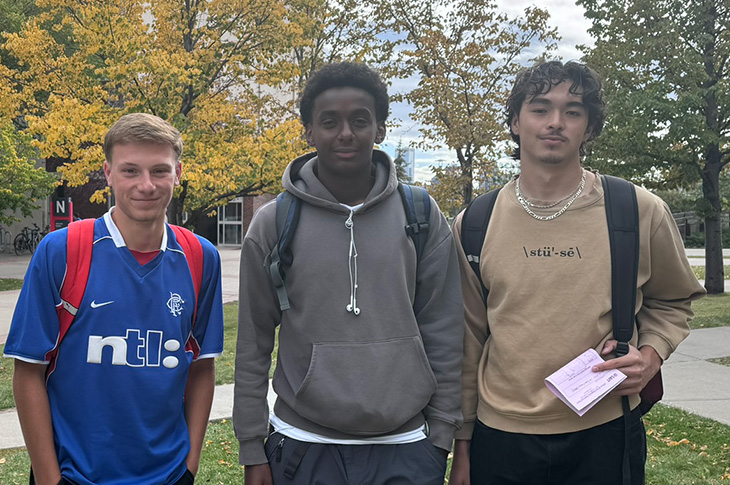 Three people pose for the photo outside standing shoulder to shoulder.