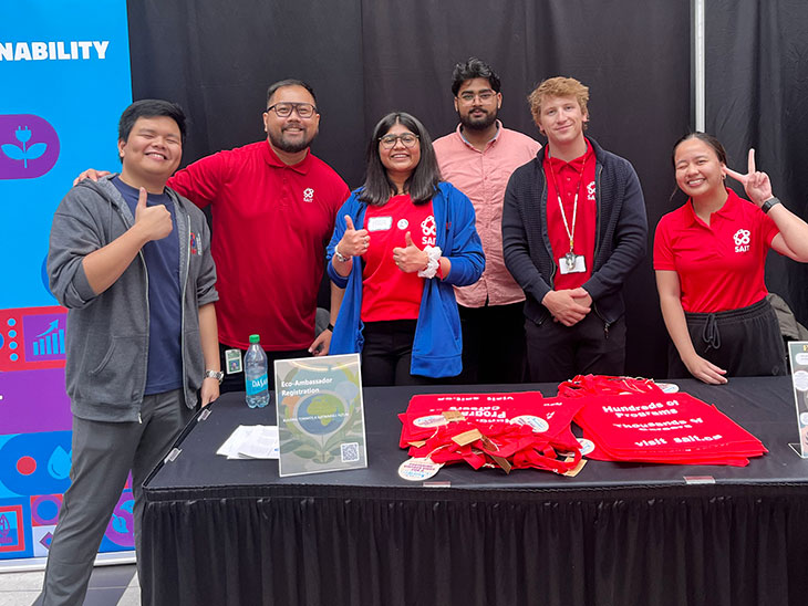 group of eco-ambassador students in red shirts behind a table/booth